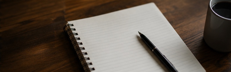 Notebook, pen and coffee on a wooden table, ready for planning